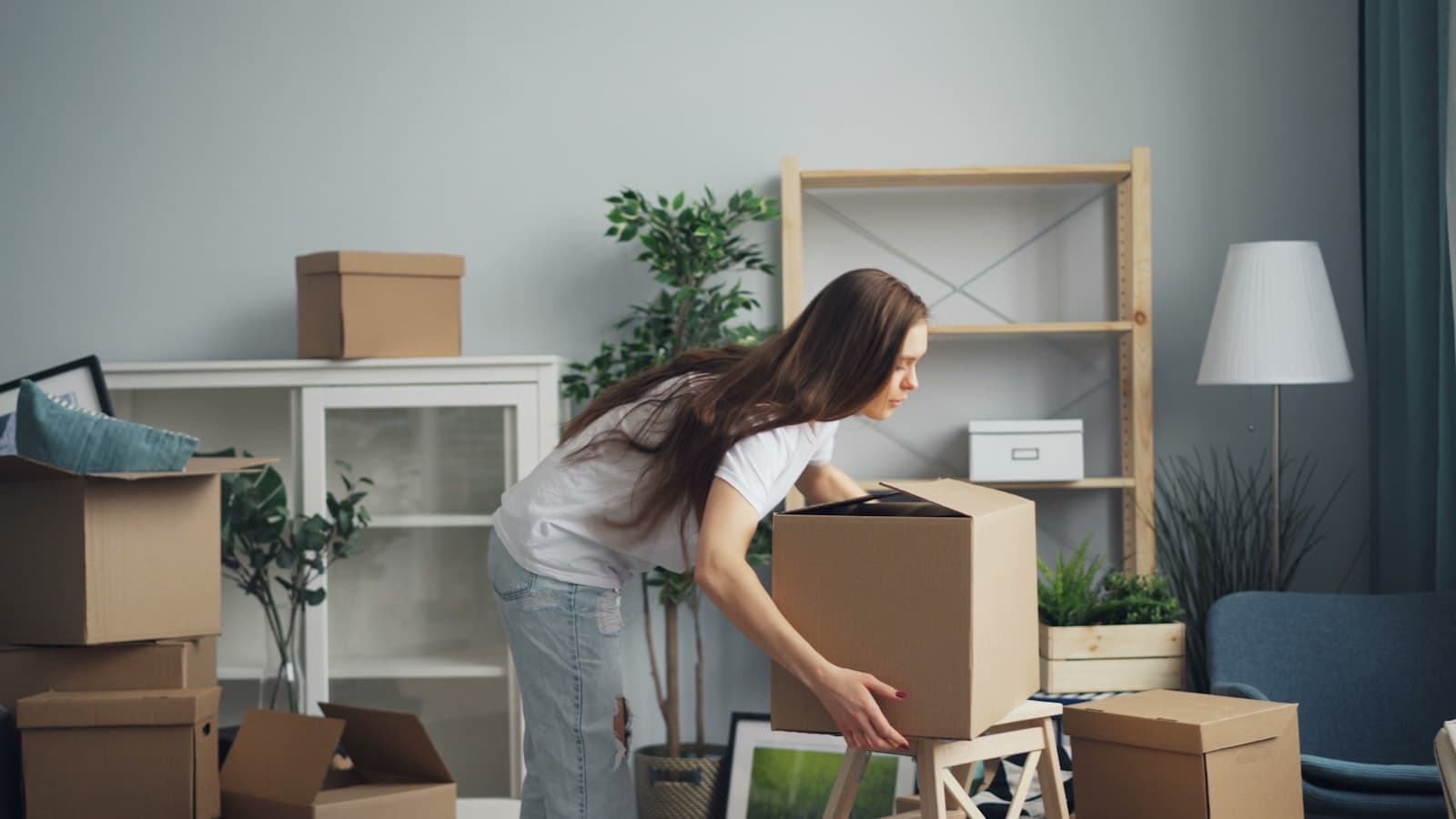 A woman surrounded by moving boxes in a new, unfamiliar apartment
