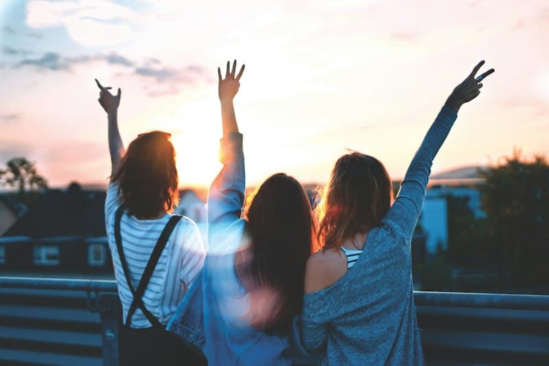 A group of friends cheering at sunset